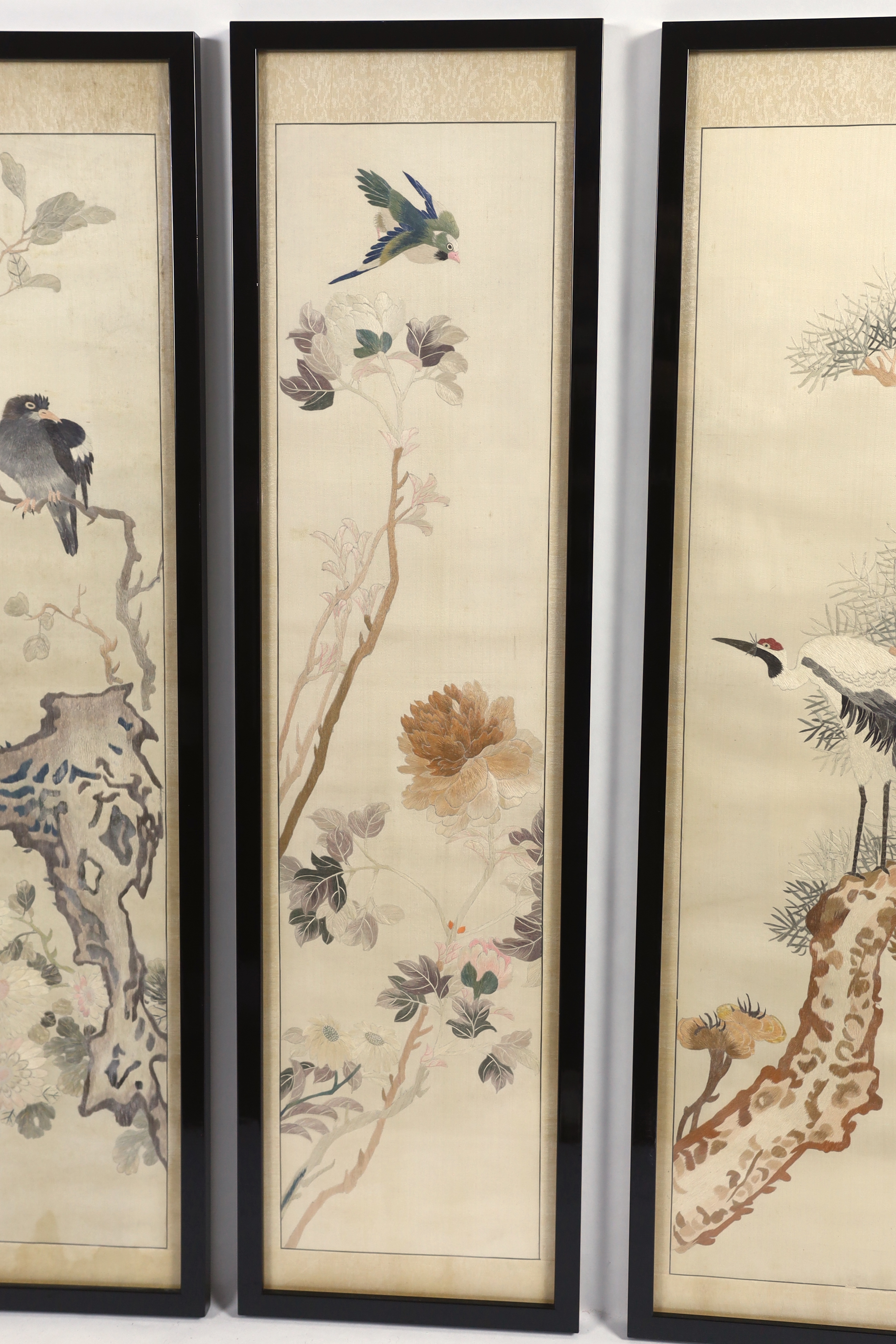 A set of four framed Chinese silk embroideries, of “The Four Seasons”, late Qing dynasty, embroidered with birds and trees and flowers, 96cm high x 22cm wide